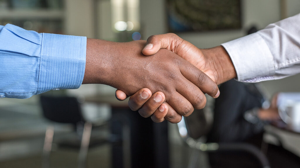 Two people in dress shirts shaking hands