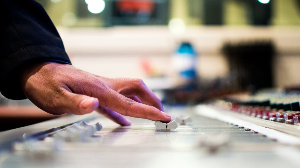 Hand controlling faders on sound desk